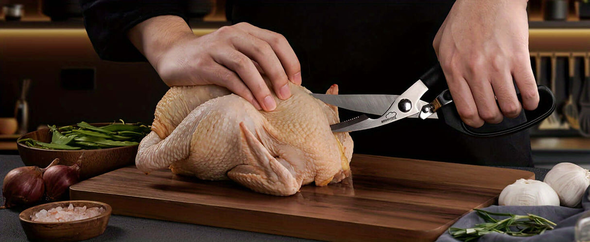 Person using kitchen scissors to cut chicken on a wooden cutting board with vegetables, showcasing cooking skills.