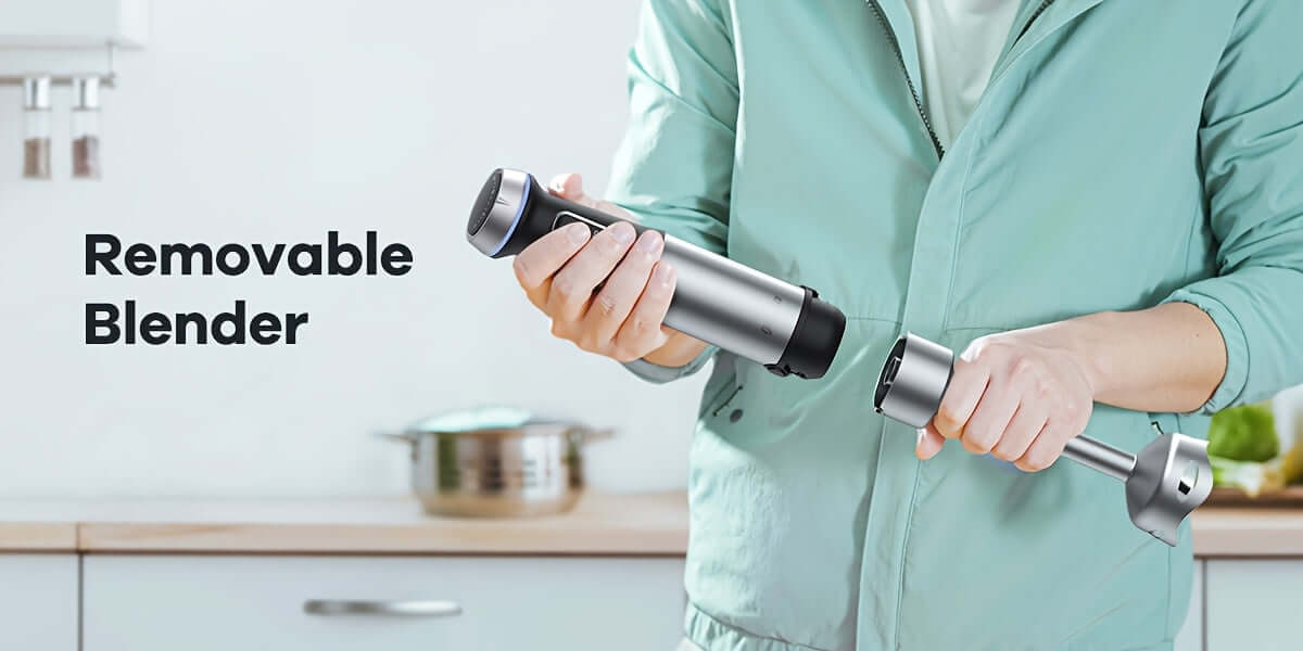 User demonstrating the removable feature of an immersion blender in a modern kitchen setting.