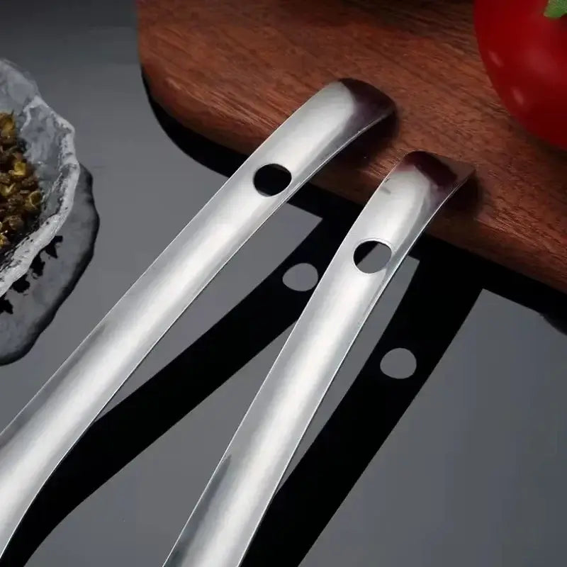 Stainless steel strainer spoon and colander tool on a wooden surface, perfect for kitchen use and cooking.