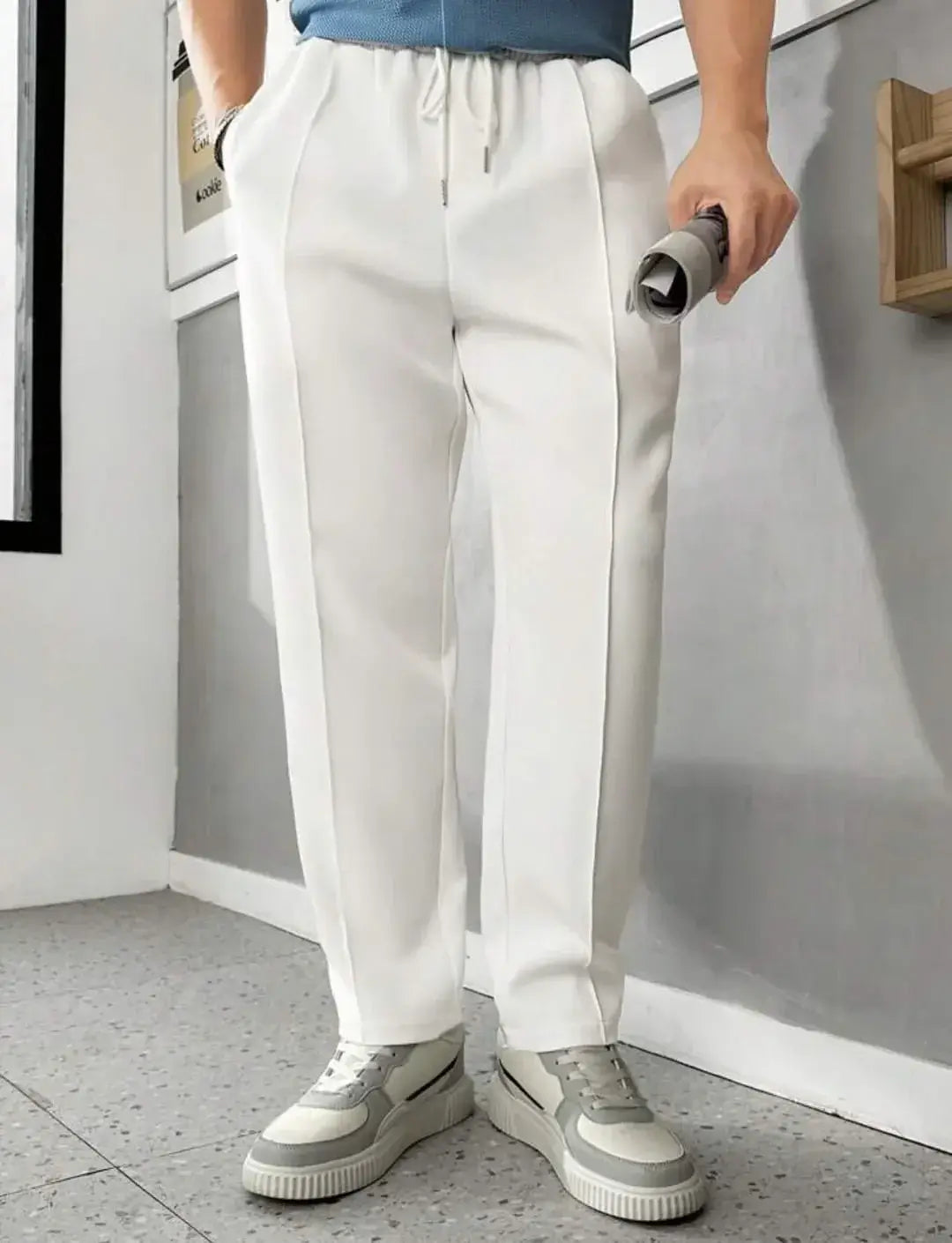 Men's casual white pants with elastic waistband, paired with a blue top and stylish sneakers, perfect for relaxed outings.