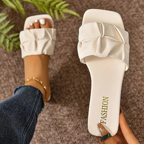 Stylish women's slide sandals in cream color with a knot detail, perfect for casual summer looks.