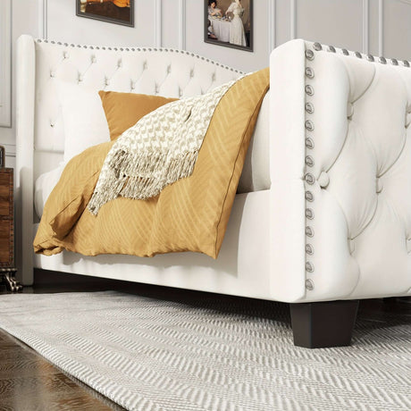 Contemporary bed frame upholstered in white with tufted design, showcasing a cozy throw blanket and soft pillow.