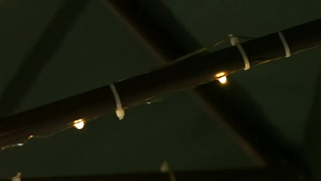 Close-up of cordless patio umbrella lights with a remote control, illuminating the structure for outdoor ambiance.