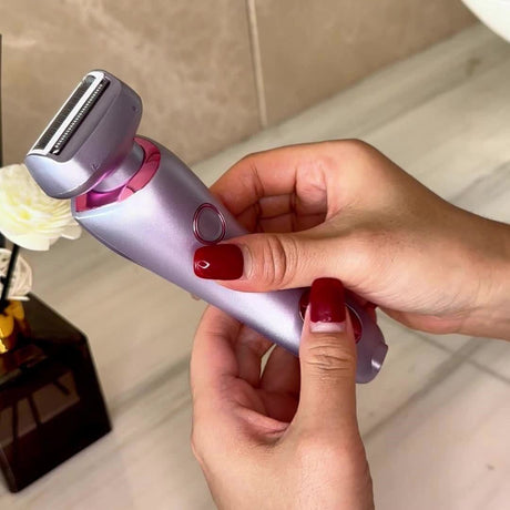 Rechargeable electric shaver for women held in hand, featuring stainless steel blades and sleek design.