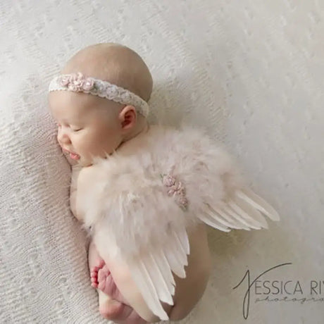 Cute newborn baby girl with angel feather wings and floral headband, perfect for photo props.