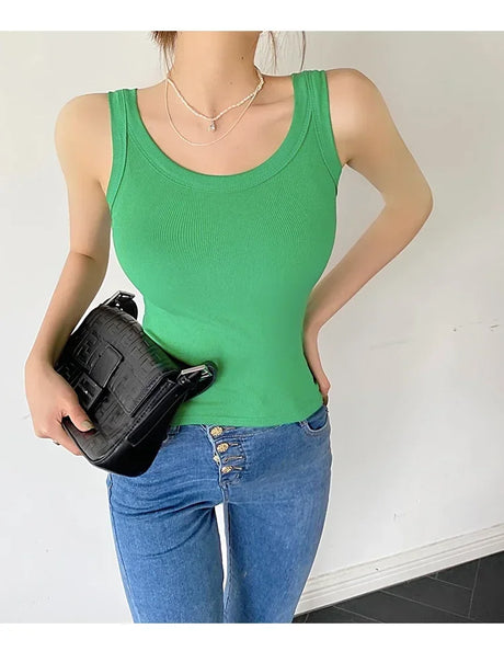Model wearing a green sleeveless ribbed tank top with a black handbag, styled in casual streetwear.