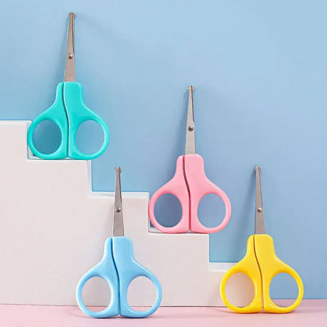 Colorful baby nail scissors in green, pink, blue, and yellow on a pastel background, ideal for newborn grooming.