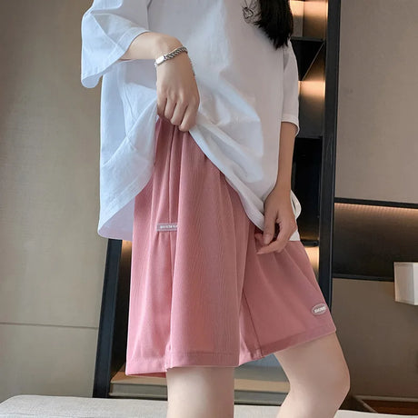 Woman wearing pink wide leg maternity capris paired with a loose white top in a modern interior setting.