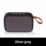 Portable outdoor Bluetooth 5.0 mini speaker in silver gray with handle for easy carrying.