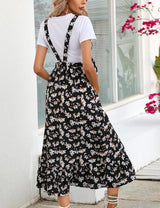 Back view of a woman wearing a floral mid-calf maternity dress paired with a white top, in a casual summer setting.