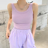 Model wearing a pastel pink sleeveless ribbed tank top paired with light lavender pants in a modern indoor setting.