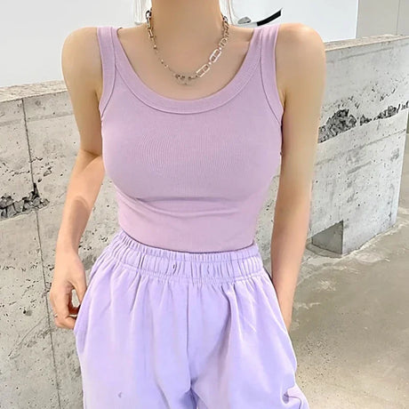 Model wearing a pastel pink sleeveless ribbed tank top paired with light lavender pants in a modern indoor setting.