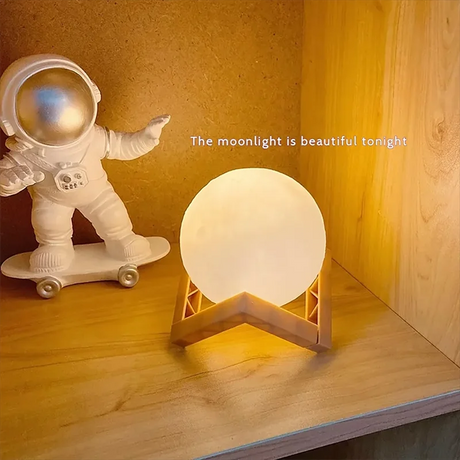LED moon galaxy book light on a wooden shelf paired with an astronaut figurine, creating a cozy decor atmosphere.