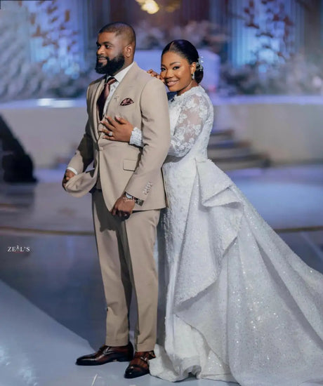 Elegant couple at a wedding, showcasing the contrasting styles of a groom in beige suit and bride in a sparkling white gown.