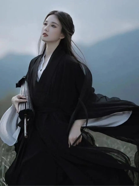 Elegant woman in a black Swordsman Hanfu costume, flowing in nature, evoking Tang Dynasty style.