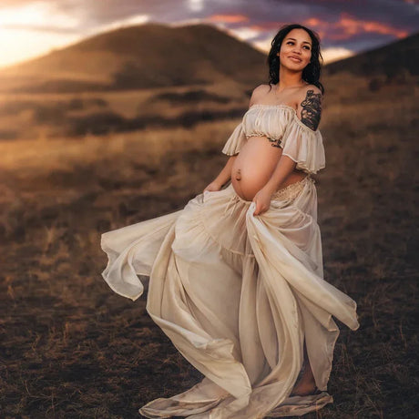 Pregnant woman in a boho two-piece maternity set posing outdoors, showcasing a flowy dress and natural scenery.