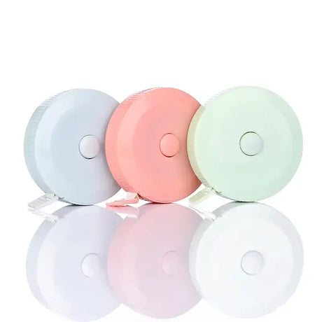 Three colorful round baby height rulers in white, pink, and green, measuring up to 1.5 meters, reflecting light.