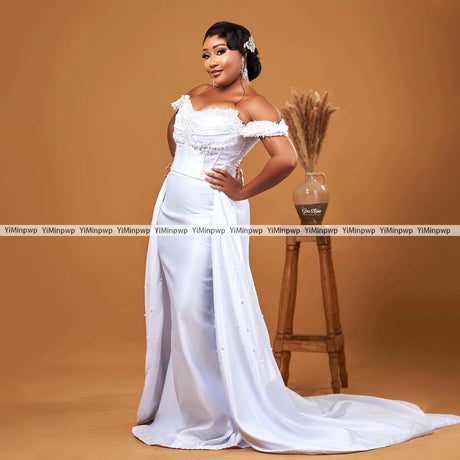 Elegant off-shoulder wedding dress with detachable train and pearl embellishments, perfect for brides.