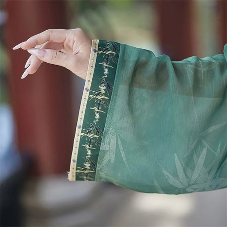 Close-up of a woman's hand wearing the green sleeve of a Hanfu cosplay dress, featuring intricate design and material details.
