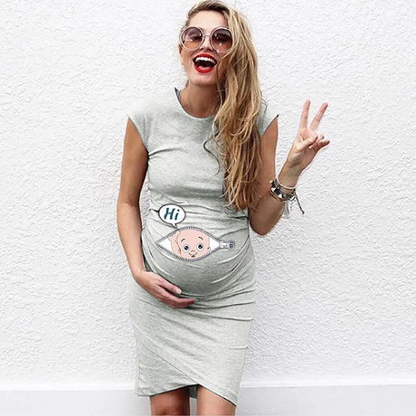 Woman in a loose casual maternity dress, peace sign, showing cartoon baby design on her belly.