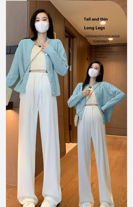 Model wearing wide-leg maternity pants and a cardigan in a stylish indoor setting.