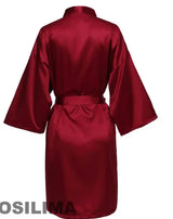Back view of a luxurious burgundy satin robe with short sleeves and a belted waist.