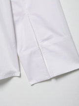 Close-up of the sleeve of an elegant white embroidered shirt, showcasing neat stitching and fabric details.