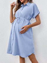 Casual summer maternity dress in light blue with button front and tie waist, ideal for expecting mothers.