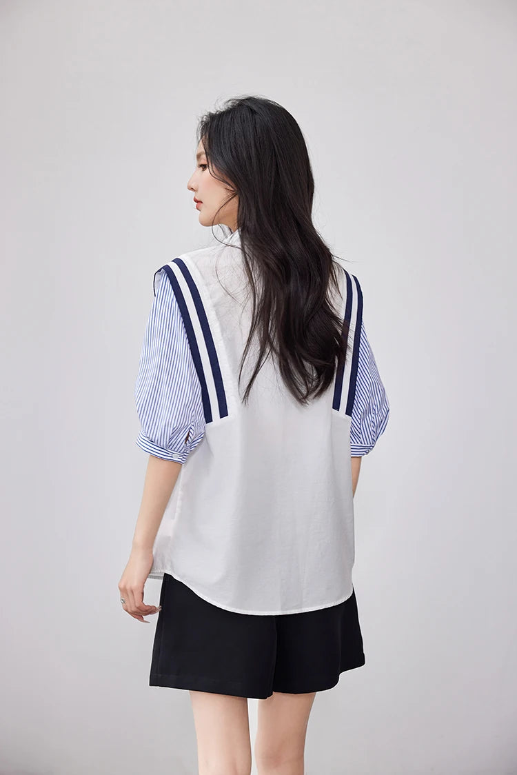 Back view of a woman wearing a colorblock chiffon shirt with striped sleeves and black shorts.