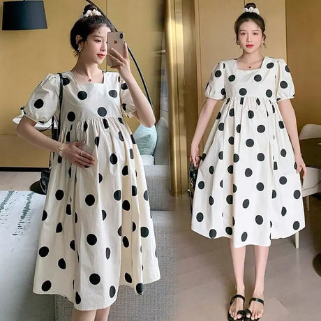Woman wearing a polka dot loose maternity dress, perfect for summer, showcasing mid-calf length and short sleeves.