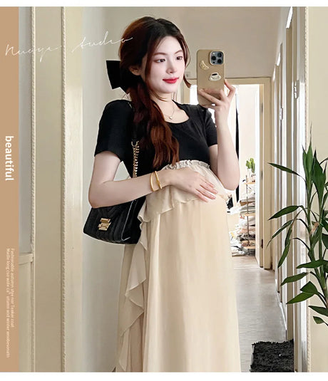 Maternity dress in black and beige styled for summer photoshoot, featuring casual chic look for expecting mothers.