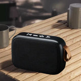 Portable outdoor Bluetooth 5.0 mini speaker on wooden table, ideal for music lovers and outdoor enthusiasts.