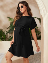 Elegant bat-sleeve maternity tunic dress in black, perfect for summer photoshoots, styled with sunglasses.