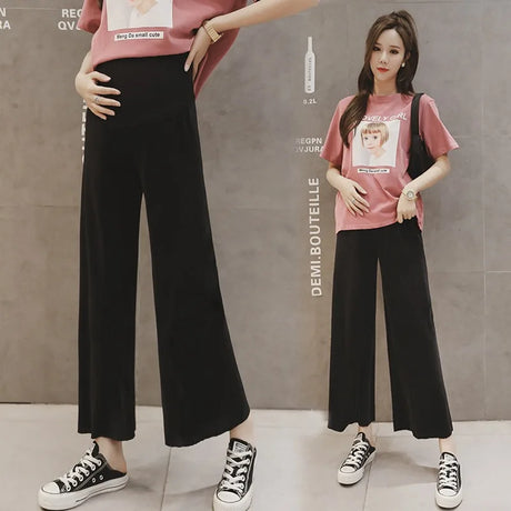 Model wearing Ice Silk Pleated Maternity Pants in black with a loose fit, paired with a casual t-shirt and sneakers.