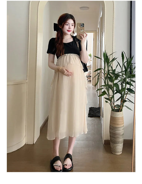 Short sleeve maternity dress in casual style, showcasing a pregnant model in a light beige dress standing indoors.