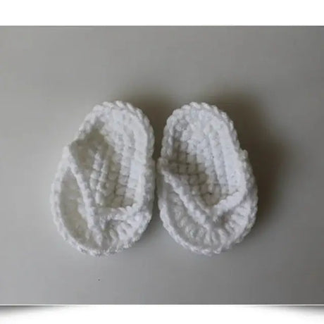 White baby slippers with a cozy knitted texture, perfect for keeping little feet warm and stylish.