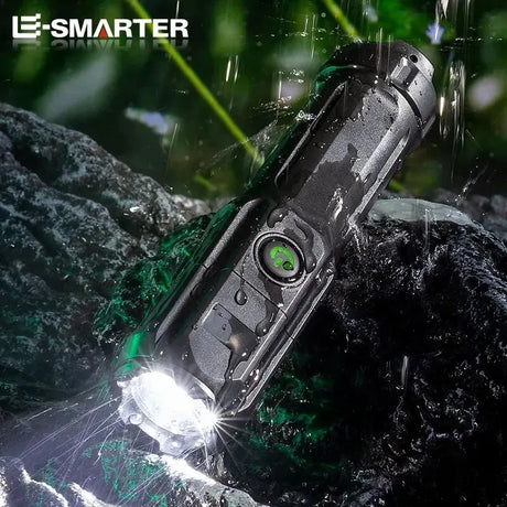 Rechargeable LED tactical flashlight by ESMARTER, waterproof design, illuminated in rain on rocky surface.