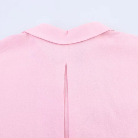 Close-up of the back neckline and pleat detail of a pink blouse with a turn-down collar.