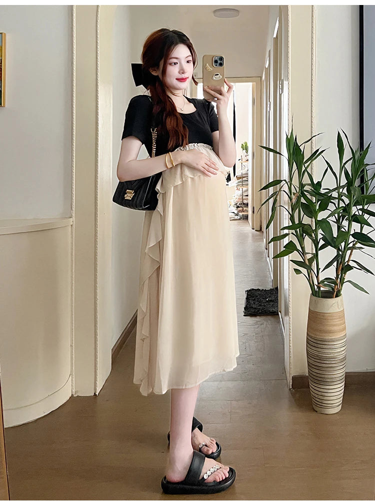 Maternity model wearing a short sleeve summer dress with ruffles, showcasing a casual style in a bright interior.