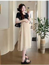 Maternity model wearing a short sleeve summer dress with ruffles, showcasing a casual style in a bright interior.