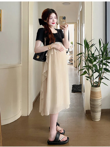 Maternity model wearing a short sleeve summer dress with ruffles, showcasing a casual style in a bright interior.