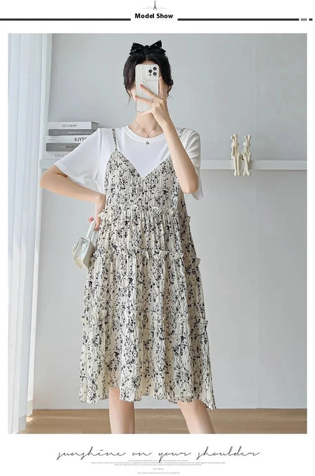 Model wearing a cute spaghetti strap layered dress with floral pattern, styled with a white t-shirt and a bow hair accessory.