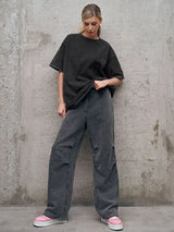 Casual women's outfit featuring a loose black t-shirt and gray wide-leg pants, styled on an urban background.