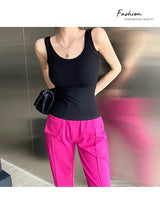 Woman wearing a black sleeveless tank top with pink trousers, showcasing a trendy streetwear style.