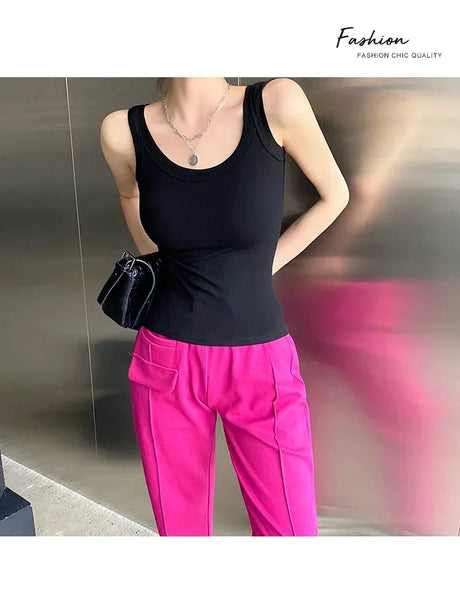 Woman wearing a black sleeveless tank top with pink trousers, showcasing a trendy streetwear style.