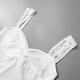 Close-up of a white lace strap on a pleated camisole tank top, showcasing delicate knit fabric and feminine design.