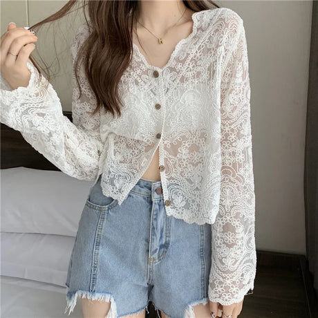 Woman wearing SheerCharm™ see-through lace sun shirt, paired with denim shorts for a stylish summer look.