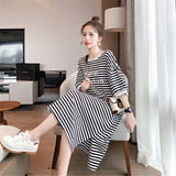 Woman wearing a striped maternity dress with boat neck and loose fit, perfect for summer and casual outings.