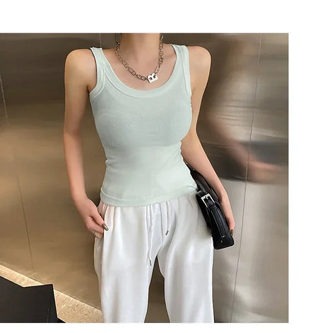 Light green sleeveless ribbed tank top styled with casual white pants, perfect for streetwear fashion.