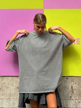 Woman wearing a loose-fitting gray casual t-shirt against a colorful backdrop, showcasing a relaxed style.
